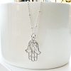 Hamsa Hand hanging on satellite link chain, dangling from a white ceramic pot