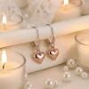 Rose Gold Heart charms on sterling silver lever backs displayed on soft silk material with soft furnishings in the background
