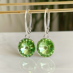 Green Peridot Silver Crystal lever back Earrings hanging on a gold bar.