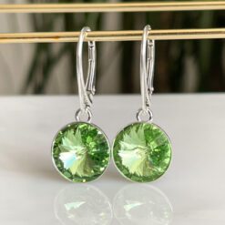 Green Peridot Silver Crystal lever back Earrings hanging on a gold bar.