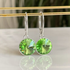 Green Peridot Silver Crystal lever back Earrings hanging on a gold bar.