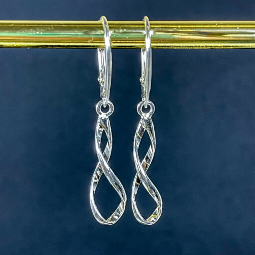 Silver Spiral Lever Back Earrings on a dark blue background hanging From a gold bar.
