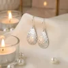 Hammered Tear Drop Silver earrings hooked over a silk material background with soft lighting